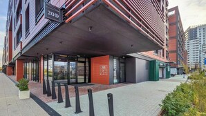 Un bâtiment moderne à la façade rouge, doté d’une entrée couverte et d’une enseigne indiquant « 20D ».