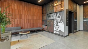 Un hall d’entrée moderne avec un mur lambrissé en bois, un canapé gris, une table ronde en bois et une grande fresque murale.