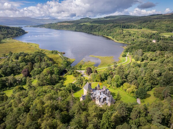 Un bâtiment historique entouré d’une végétation luxuriante et bordé d’un lac.