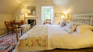 Un dormitorio con una cama grande, un escritorio, una silla, una chimenea y una ventana.