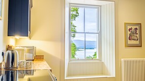 Una cocina con ventana, tetera, tostadora y radiador.