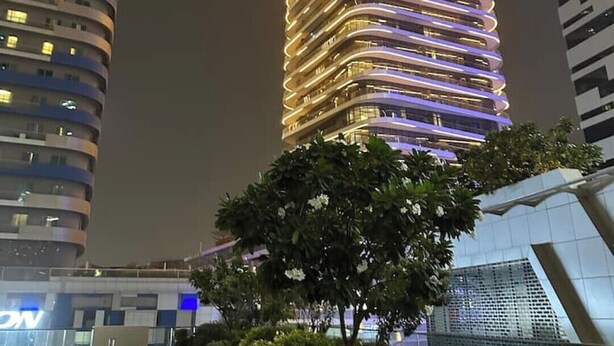 Um edifício moderno com fachada curva e janelas iluminadas.