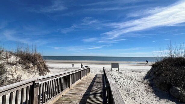 A wooden boardwalk leading to a sandy beach with a clear blue sky. - Salty Smiles (Hilton Head Island)