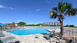 A large outdoor swimming pool with lounge chairs and a palm tree. - Salty Smiles (Hilton Head Island)
