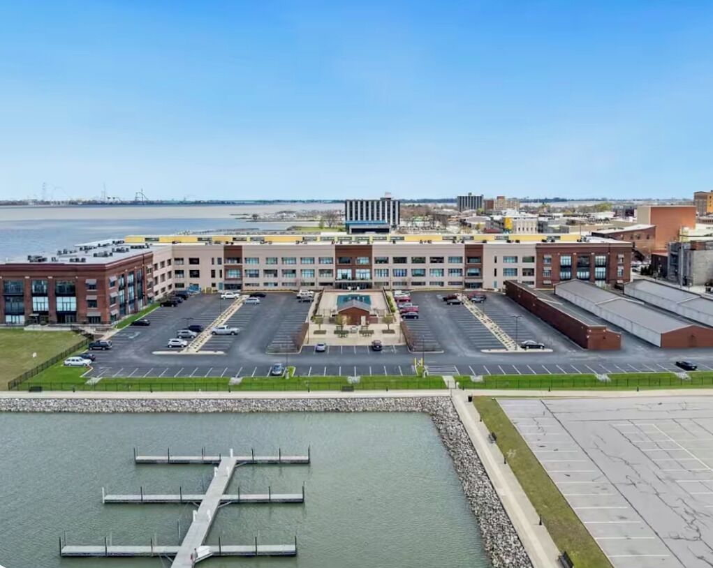 Un edificio de varios pisos con un patio central, estacionamiento y vista al agua.