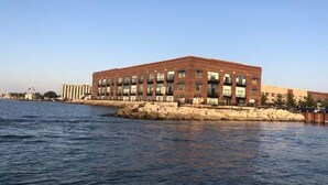 Un edificio frente al agua con fachada de ladrillo, varias ventanas y techo plano.