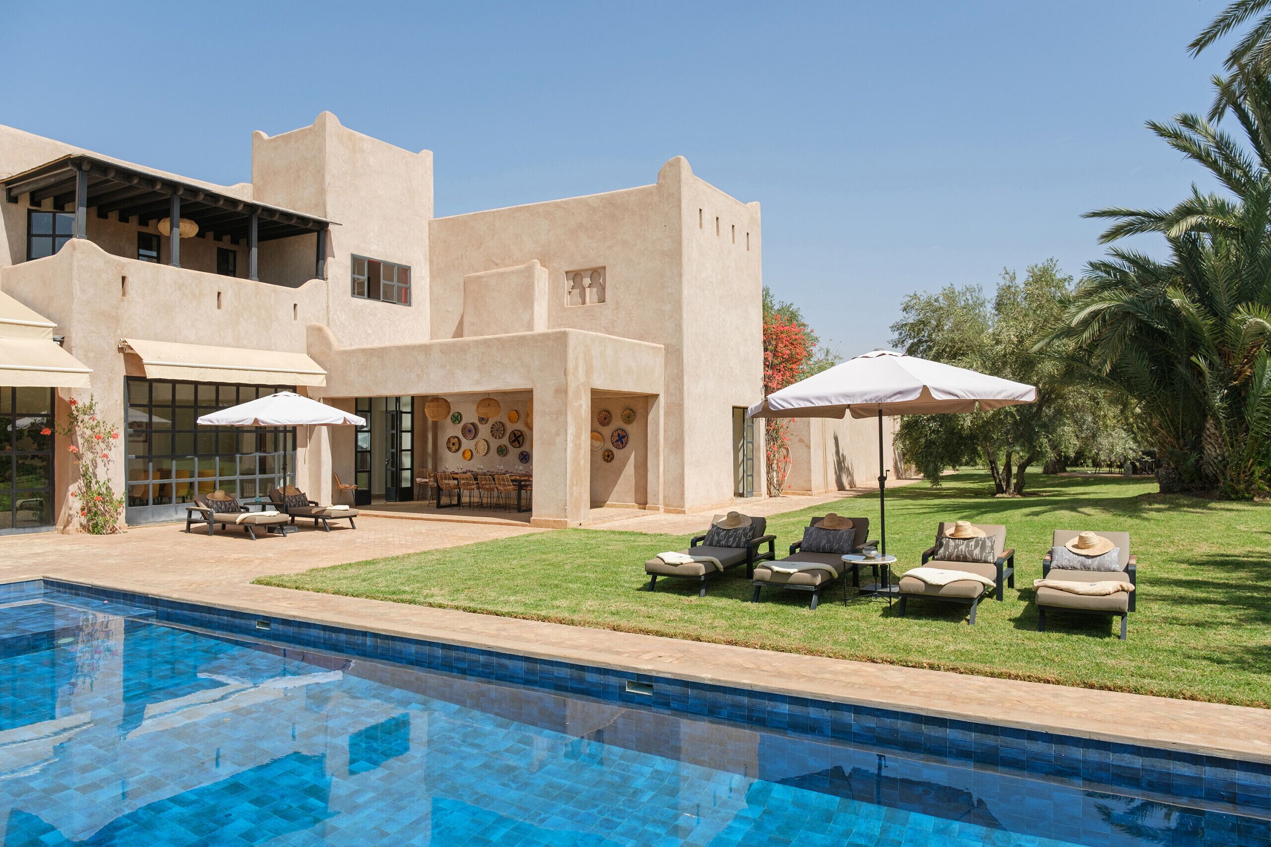 A modern house with a swimming pool, outdoor seating, and a well-maintained lawn.