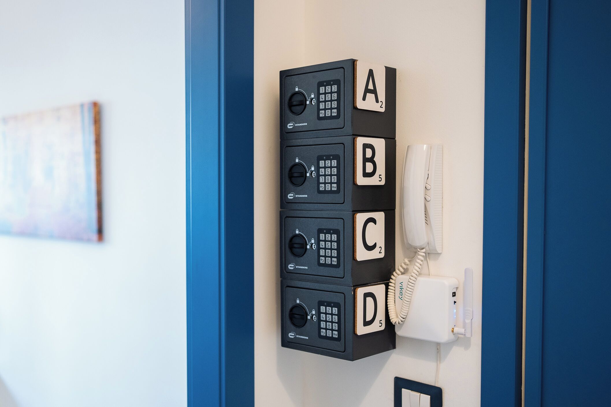 Um telefone fixado na parede com quatro caixas numeradas identificadas pelas letras A, B, C e D.