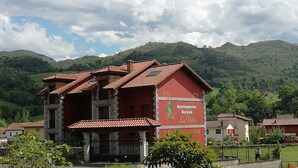 A red building with a sign reading "Apartamentos Rurales La Vina" in a rural setting with mountains in the background. - Rural Apartments La Viña (Apartment number 8) (Cangas de Onis)