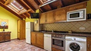 A kitchen with wooden cabinets, a microwave, an oven, and a washing machine. - Rural Apartments La Viña (Apartment number 8) (Cangas de Onis)