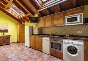 Eine Küche mit Holzausstattung, einer Mikrowelle, einem Backofen und einer Waschmaschine.