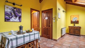 A dining area with a table set for two, a coffee pot, and a fruit basket. There are two wooden doors and a radiator on the wall. - Rural Apartments La Viña (Apartment number 8) (Cangas de Onis)