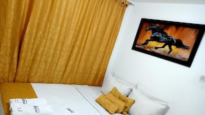 Une chambre d’hôtel avec un lit, un tableau représentant un cheval et un rideau.