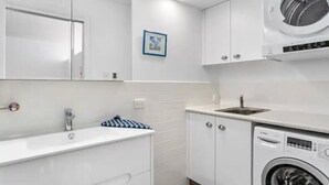 Casa de banho moderna com lavatório branco, espelho e máquina de lavar Bosch.