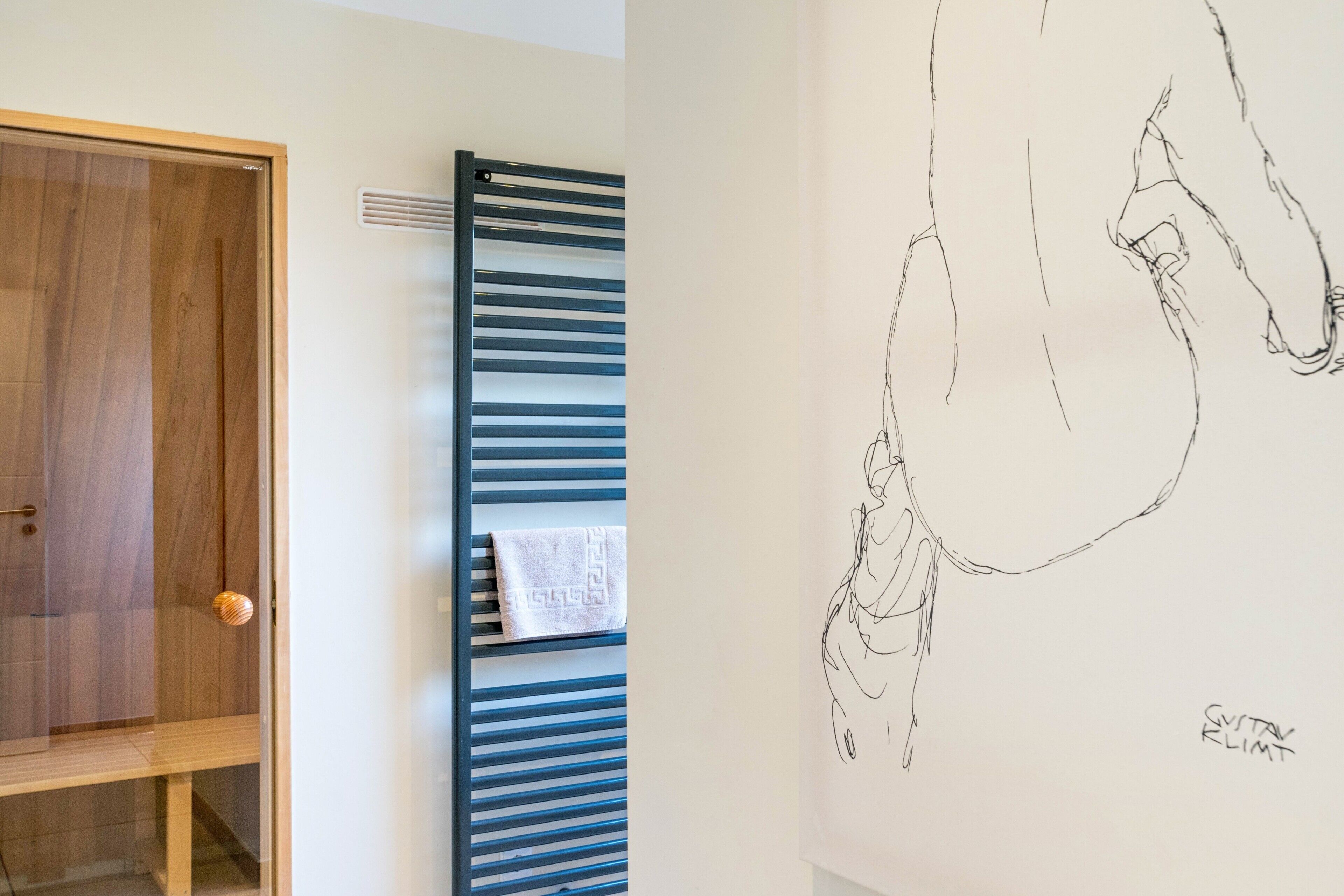 A room with a wooden door, a towel rack with a towel, and a wall with a sketched drawing.