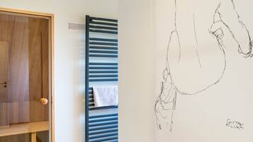 A room with a wooden door, a towel rack with a towel, and a wall with a sketched drawing.