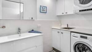 Un baño moderno con un lavamanos blanco, un espejo y una lavadora Bosch.