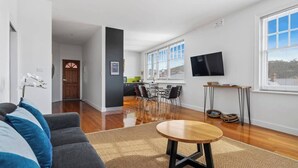 Un salon moderne avec un canapé gris, une table basse ronde en bois et un coin repas comprenant une table et des chaises.