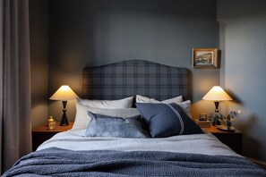 A neatly made bed with a plaid headboard, two bedside lamps, and a framed picture on the wall. - Argyle North Boutique North View (North Hobart)