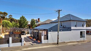 Une maison à deux étages avec une allée couverte et un espace de stationnement fermé par un portail.