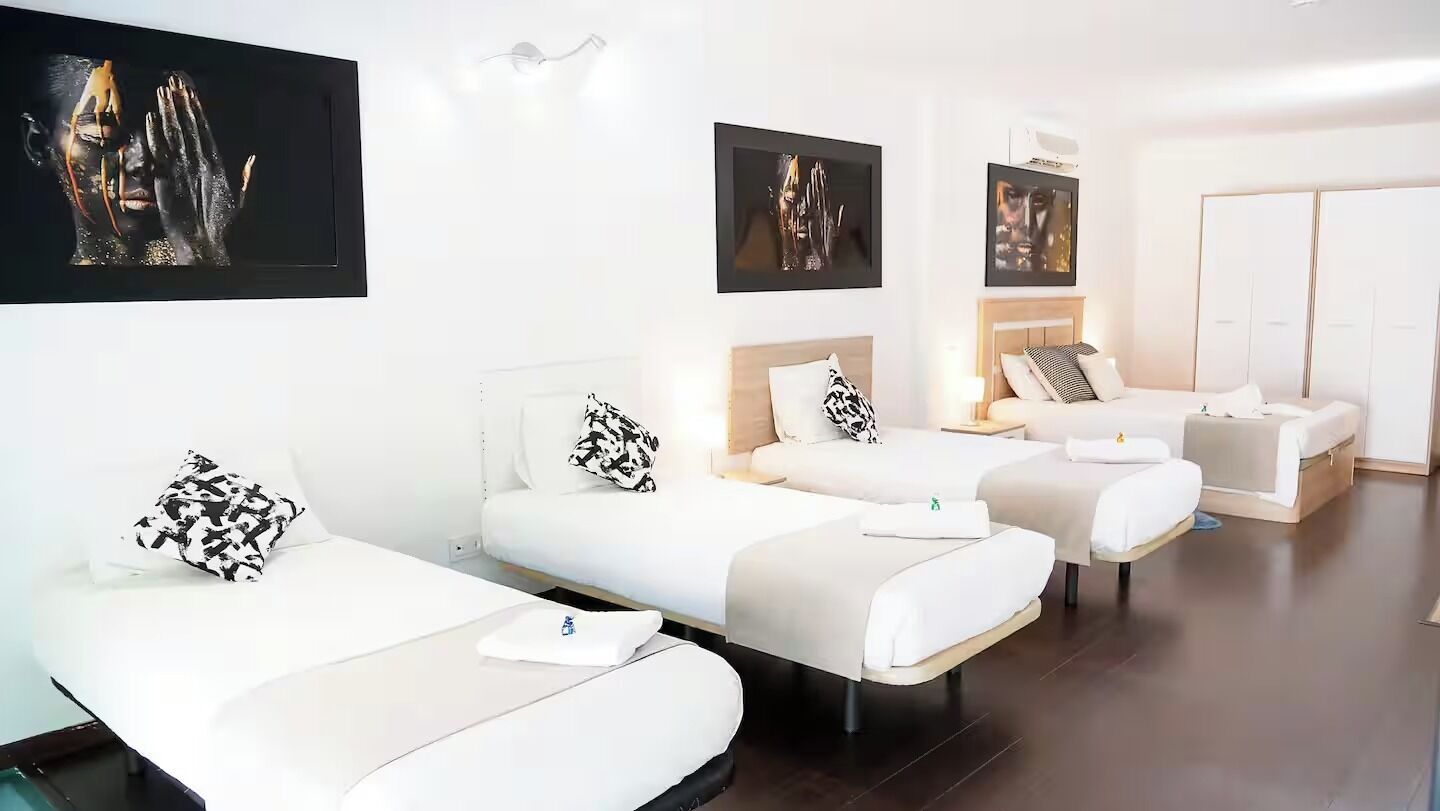 Una habitación de hotel con tres camas individuales, un sofá y un armario.