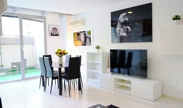 A modern living room with a dining area, a flat-screen TV, and artwork on the walls. - Seasonal Living Oshun Madrid Norte (Madrid)