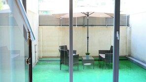 A glass-walled room with a green carpet, wicker furniture, and a ceiling fan. - Seasonal Living Oshun Madrid Norte (Madrid)