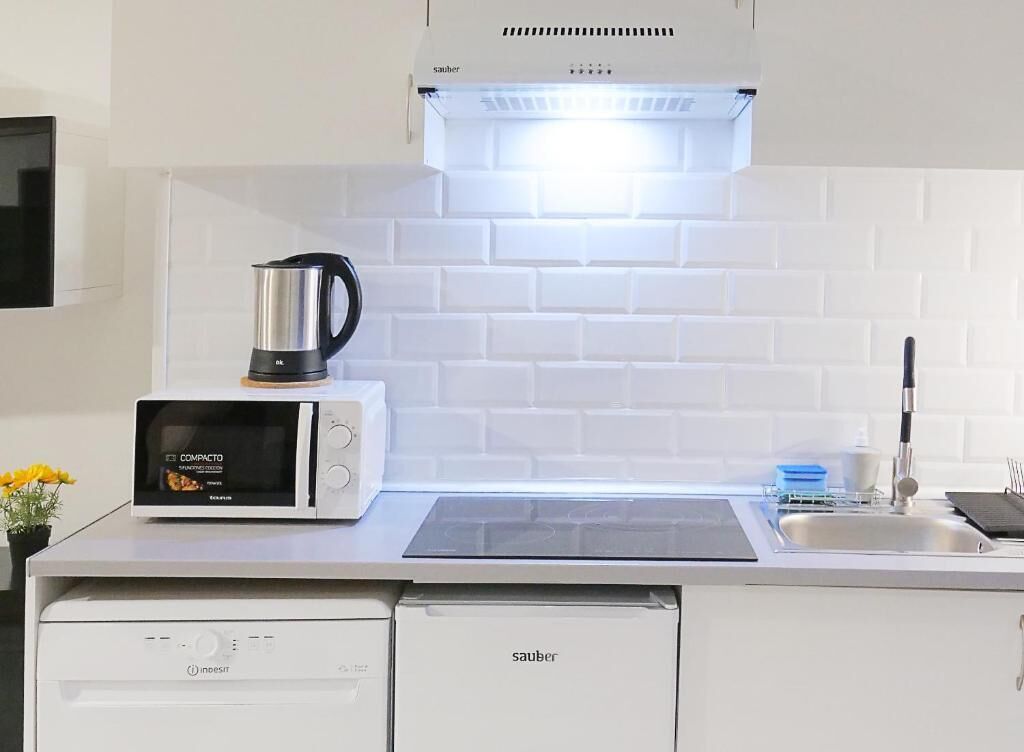 Una cocina compacta con microondas, cafetera y lavavajillas.