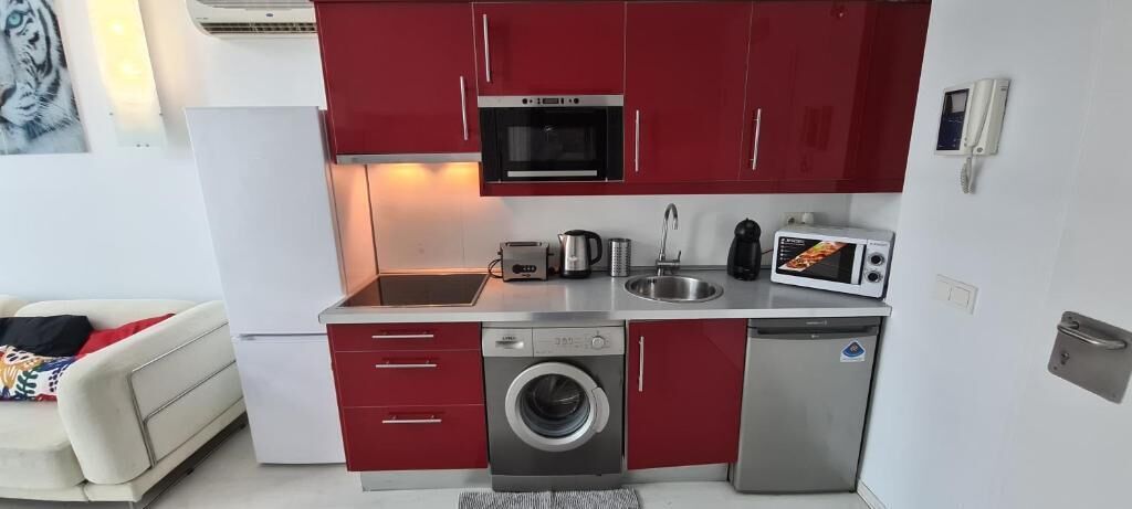 A compact kitchen with a washing machine, microwave, and toaster.
