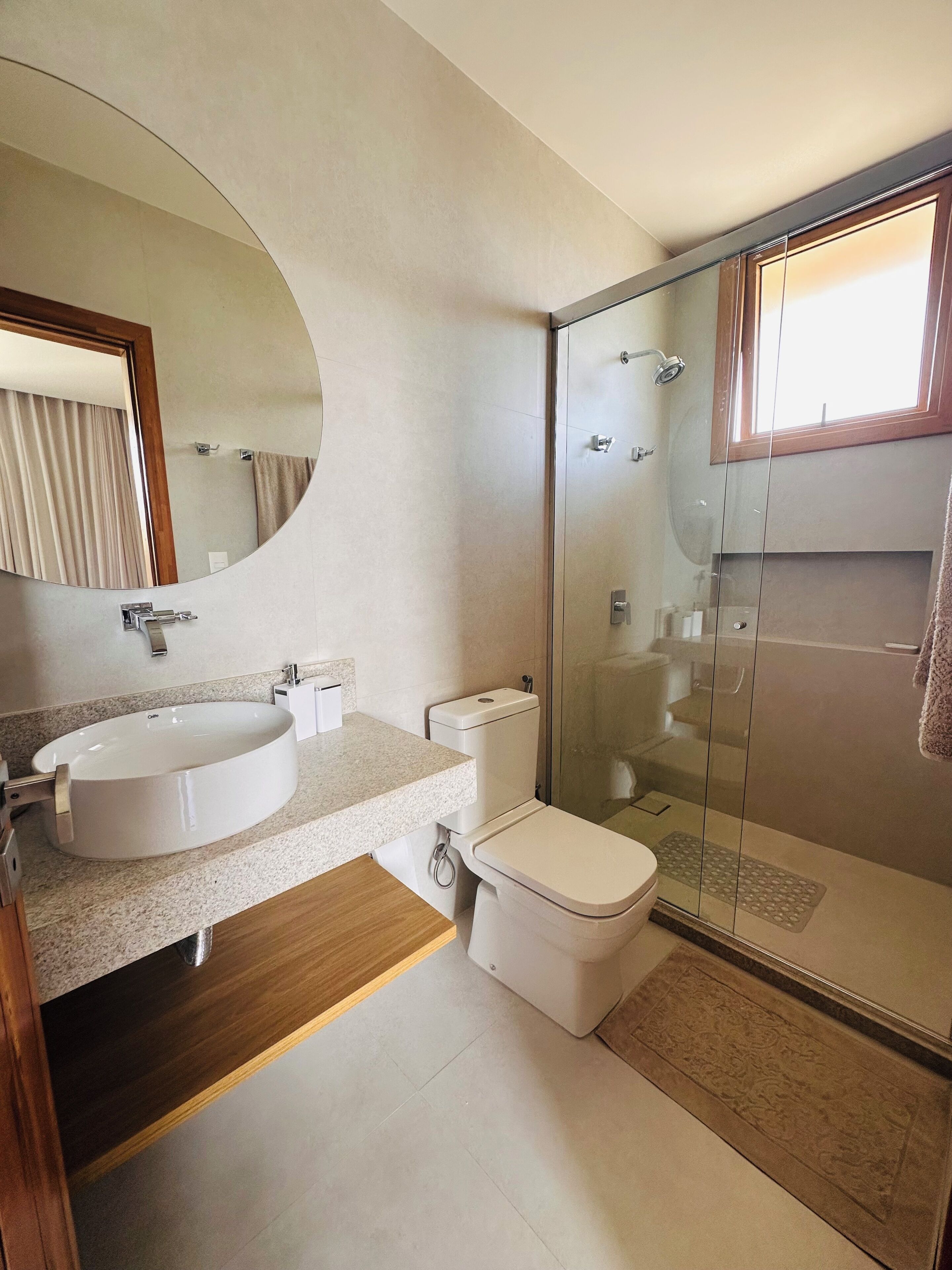 Un baño moderno con lavamanos independiente, inodoro y ducha con mampara de vidrio.