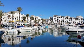 A marina with boats docked, surrounded by white buildings with balconies and palm trees. - Luxury Penthouse with Big Terrace and Seaviews (Manilva)