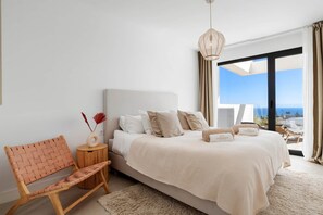 A bedroom with a bed, a chair, a bedside table, and a view of the ocean. - Luxury Penthouse with Big Terrace and Seaviews (Manilva)