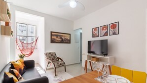 Een moderne woonkamer met een bank, een eettafel gedekt voor twee personen, een televisie en een hangmat.