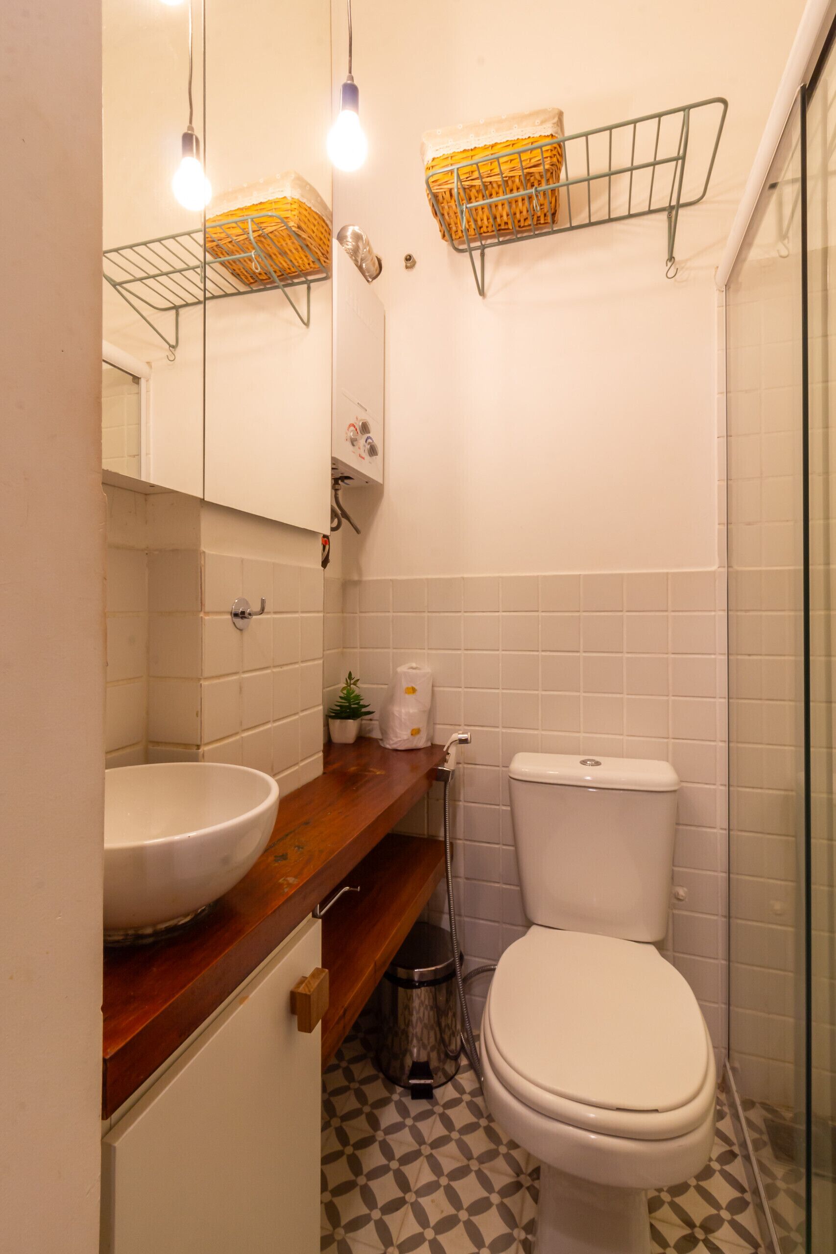 Un baño con lavamanos blanco, inodoro, espejo y zona de ducha.