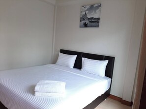 A neatly made bed with white linens and pillows, a black headboard, and a framed picture of a cityscape on the wall. - Phenwaree Amphawa Resort by Zuzu (Samut Songkhram)