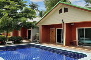 Ein Haus mit Swimmingpool, einer Veranda und einer Tür.