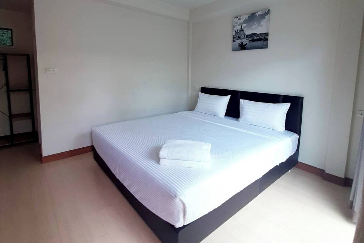 A large bed with white linens and a dark headboard in a hotel room.