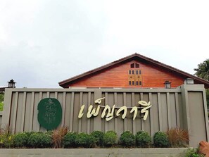A building with a wooden facade and a sign with large, stylized text. - Phenwaree Amphawa Resort by Zuzu (Samut Songkhram)