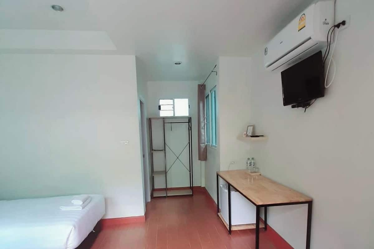 A hotel room with a bed, a desk, a TV, and a wardrobe.