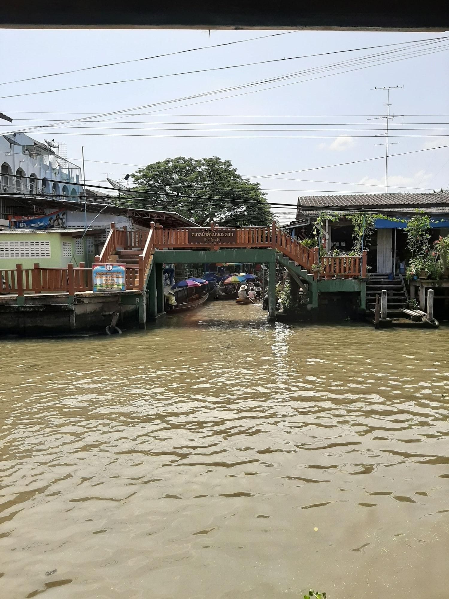 A wooden bridge over a river with boats and people.