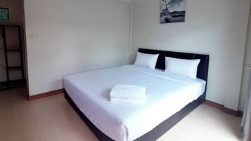 Un grand lit avec du linge de lit blanc et une tête de lit sombre, dans une chambre d’hôtel.