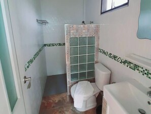 Een badkamer met douche, toilet en wastafel.