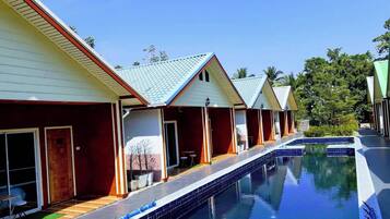 A row of single-story buildings with a swimming pool in the foreground.