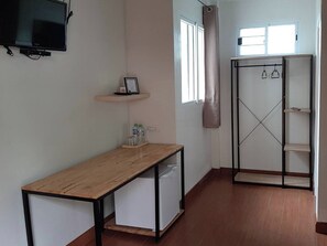 A room with a wooden desk, a white cabinet, a TV mounted on the wall, a window with a curtain, and a wardrobe with shelves. - Phenwaree Amphawa Resort by Zuzu (Samut Songkhram)