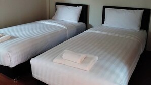 Two single beds with white linens and pillows, a wooden floor, and a plain wall. - Phenwaree Amphawa Resort by Zuzu (Samut Songkhram)