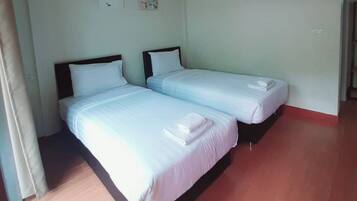A hotel room with two beds, a wooden floor, and a door.