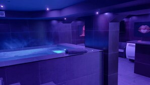 A modern spa area with a large hot tub, a steam shower, and a massage table. - Love Room—Air-Conditioned Jacuzzi Area / Massage Table (L'Escarène)