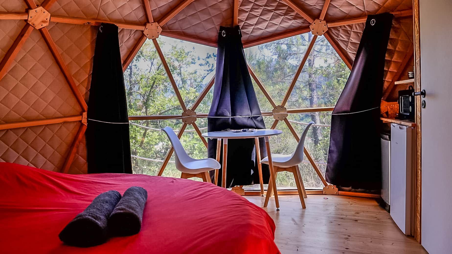 Une pièce confortable avec un lit, une petite table, deux chaises et une vue sur l’extérieur.