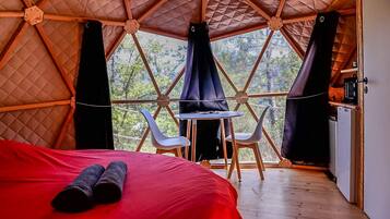 Une pièce confortable avec un lit, une petite table, deux chaises et une vue sur l’extérieur.