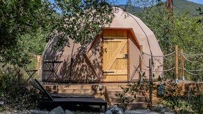 A dome-shaped tent with a wooden door, surrounded by trees and a wooden deck. - Dome & Balneotherapy (L'Escarène)